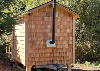 Sauna en bois Essentiel Bois Adejo Sàrl vu de l’extérieur avec conduit de poêle