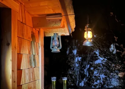 Ambiance nocturne d’un sauna en bois Essentiel Bois Adejo Sàrl avec lanternes et boissons