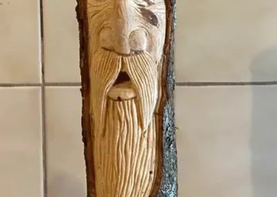 Sculpture de visage taillée dans un tronc de bois avec écorce – Essentiel Bois Adejo Sàrl