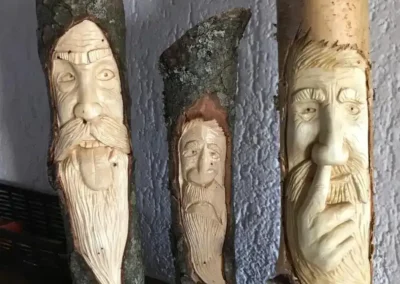 Visages sculptés dans des morceaux de bois – Essentiel Bois Adejo Sàrl