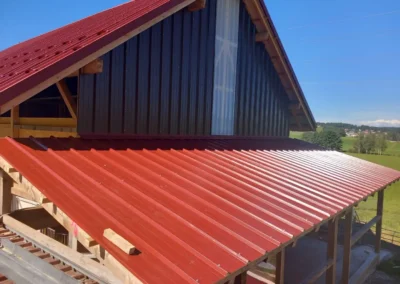 Pose de toiture en tôle profilée rouge sur charpente bois – Essentiel Bois Adejo Sàrl