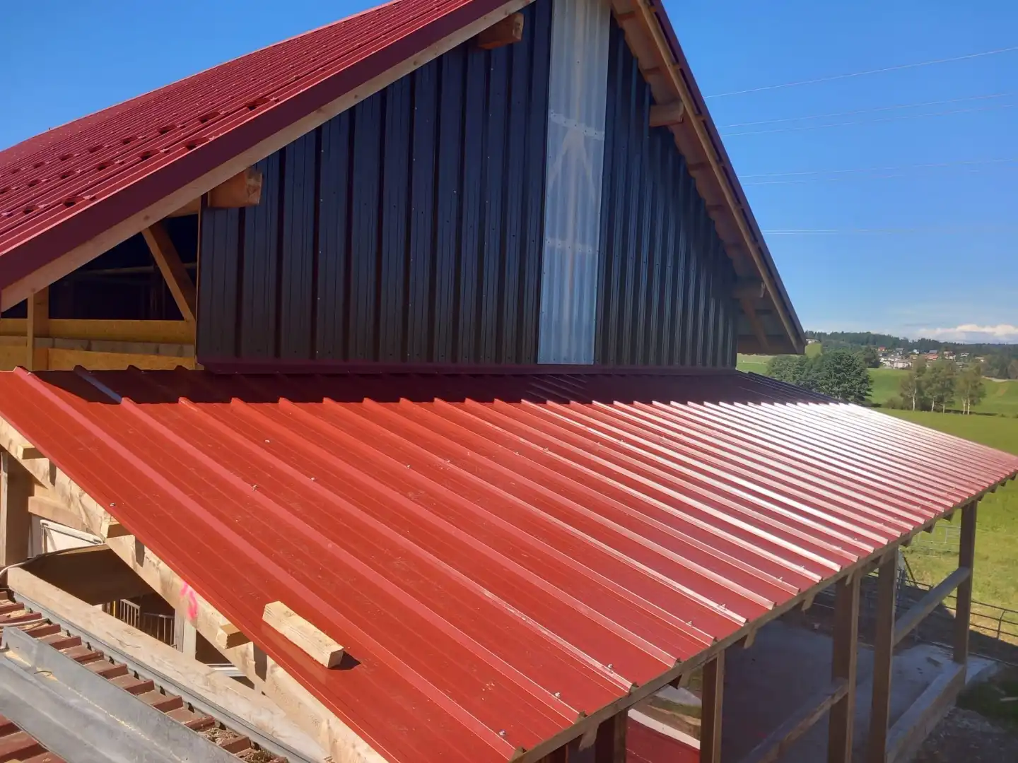 Pose de toiture en tôle profilée rouge sur charpente bois – Essentiel Bois Adejo Sàrl